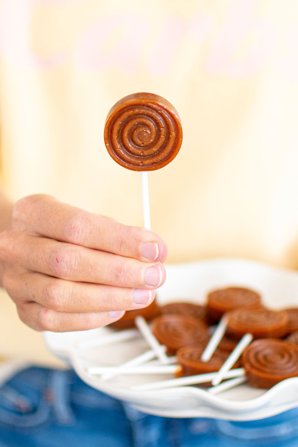 woman holding a caramel lollipop.