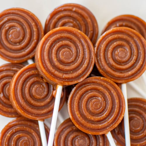 homemade caramel lollipops on a white plate.