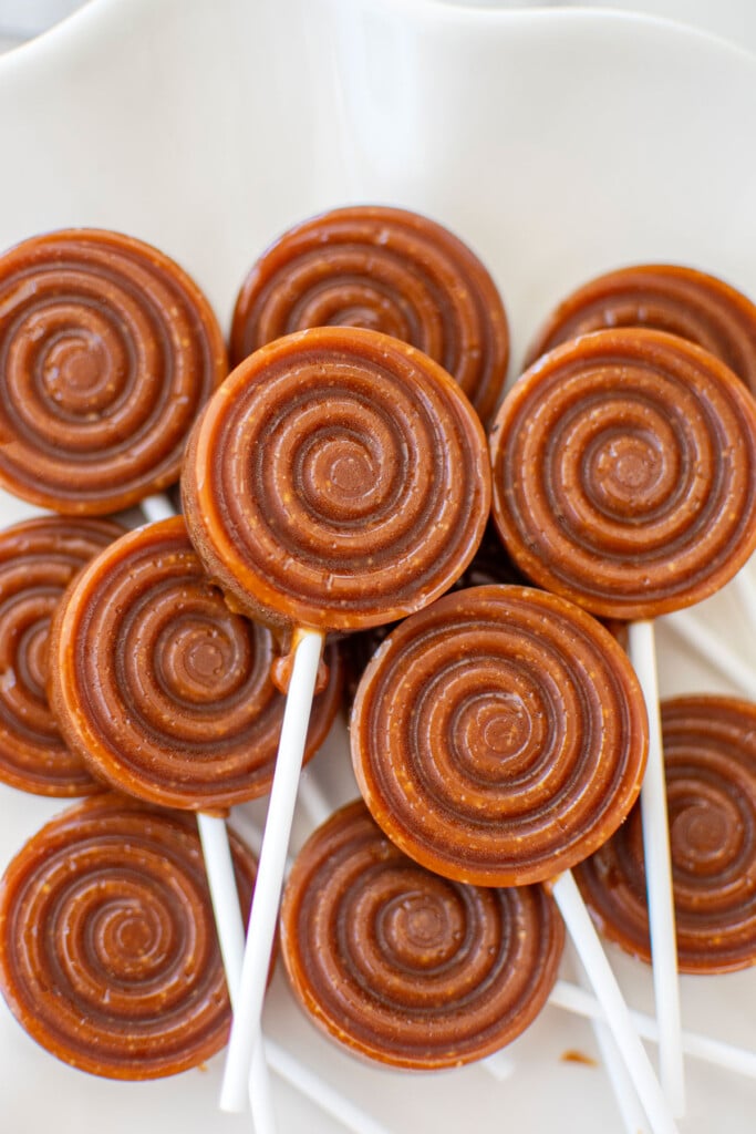 homemade caramel lollipops on a white plate.