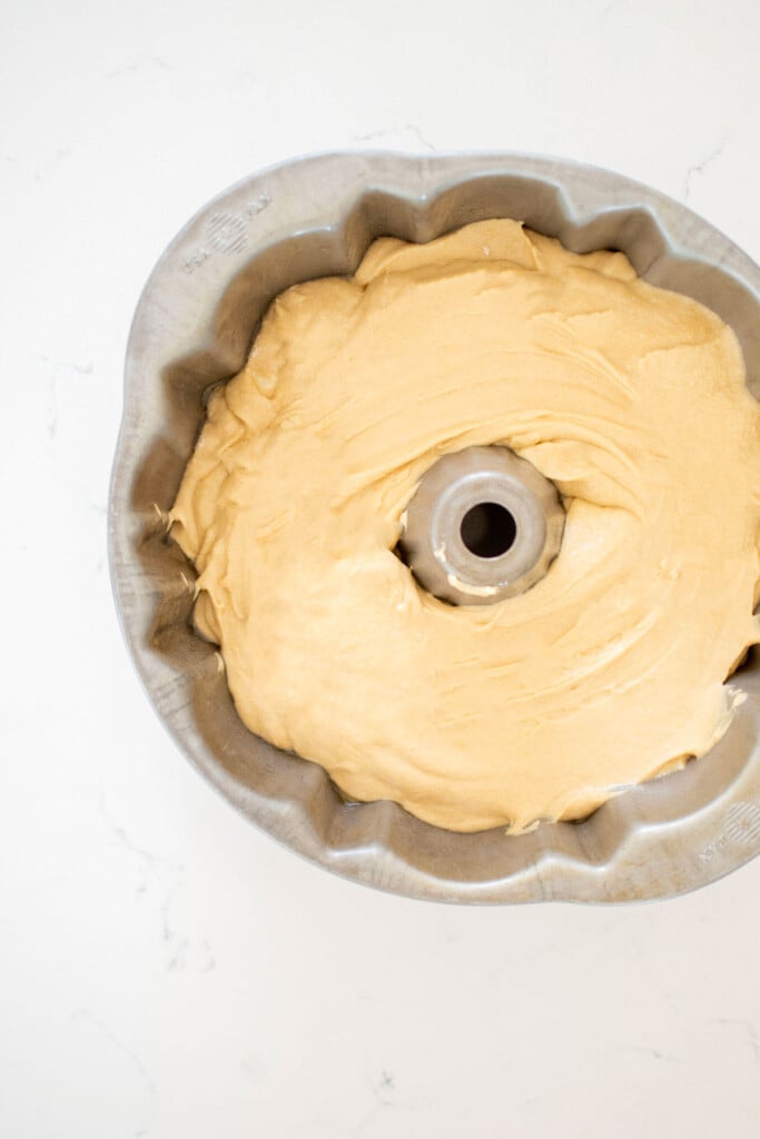 strawberry donut pound cake batter in a bundt pan on a white marble counter.