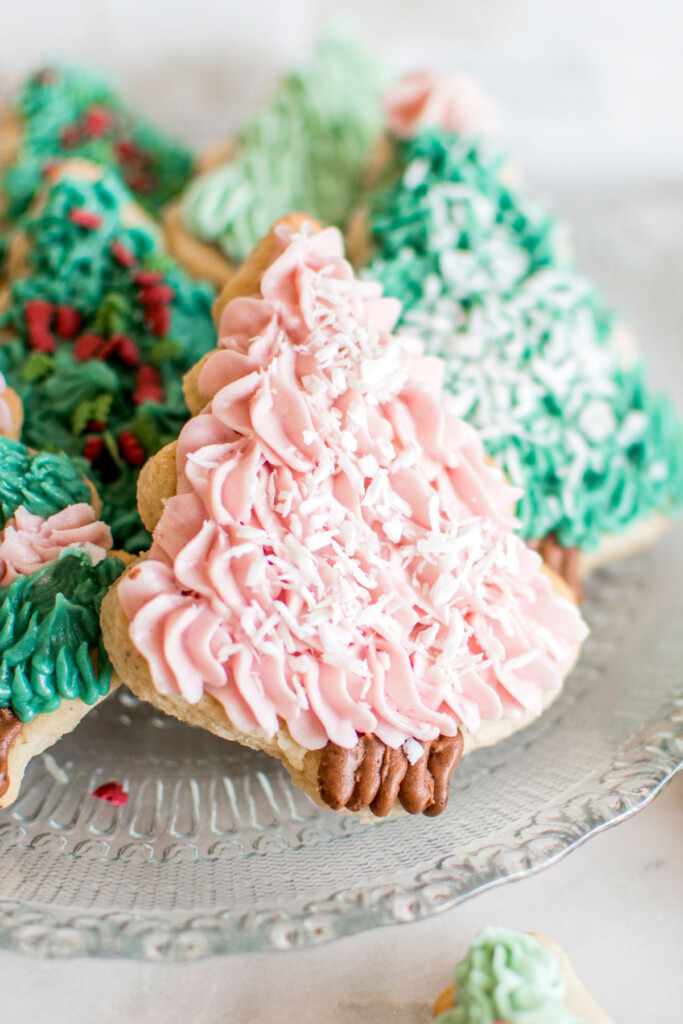 pink tree sugar cookie on a plate with other tree cookies.