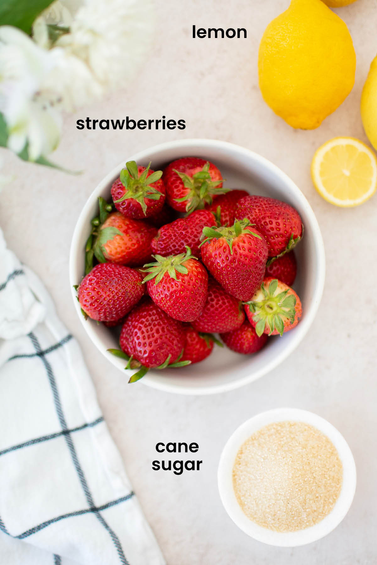 individual ingredients for organic strawberry jam laid out against a white background.