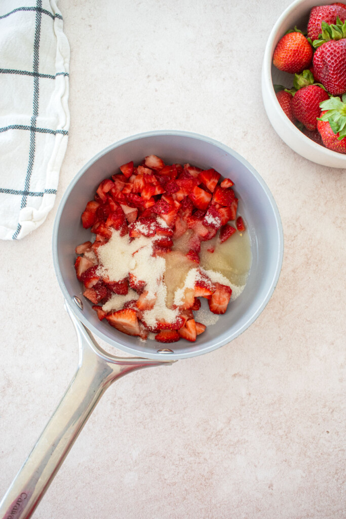 small pot with chopped strawberries, cane sugar and lemon juice.