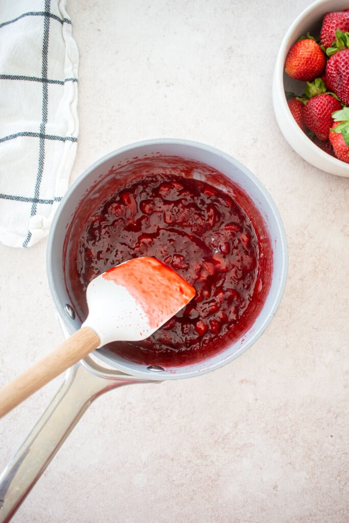 homemade strawberry jam in a small pot with a spatula.