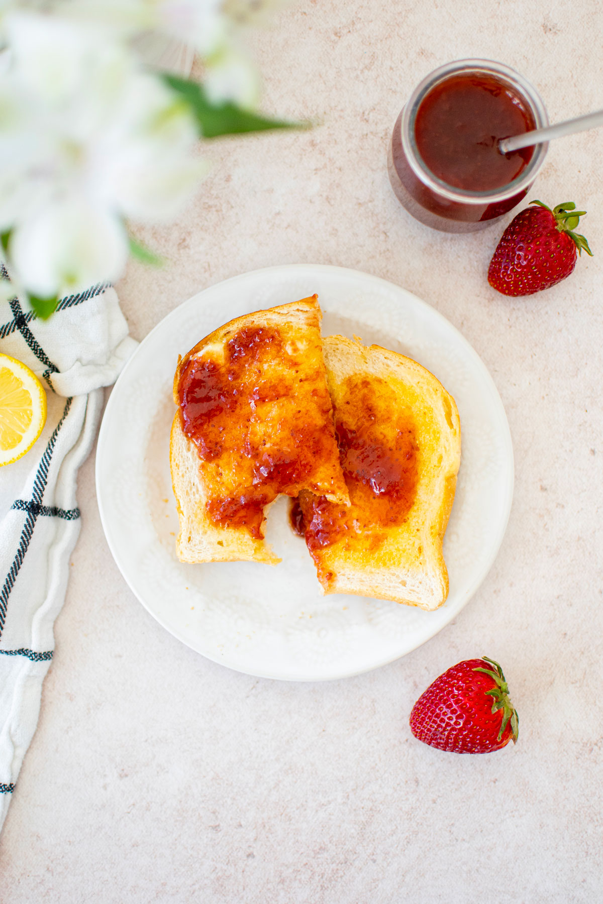 organic strawberry jam on sourdough toast on a white plate.