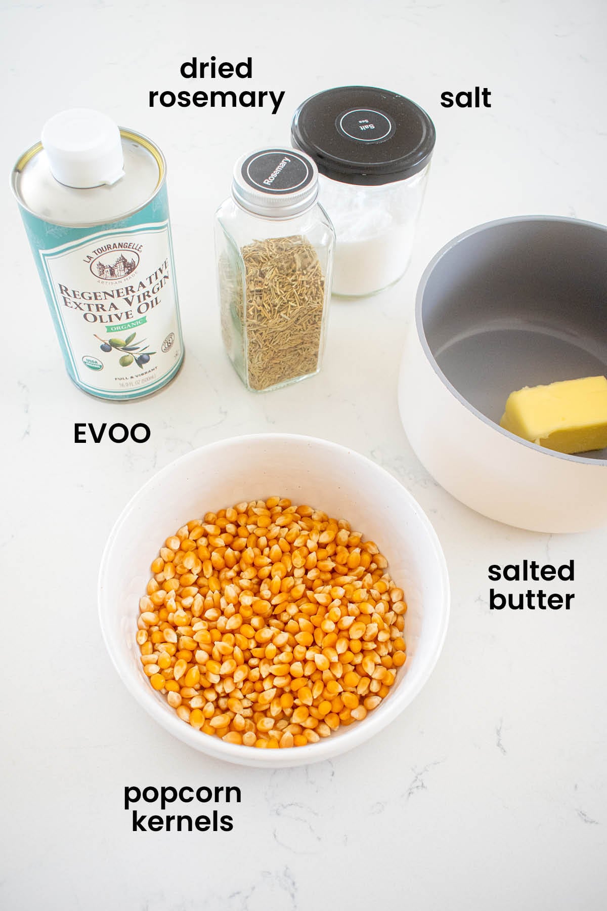 individual ingredients for rosemary sea salt popcorn laid out against a white background.