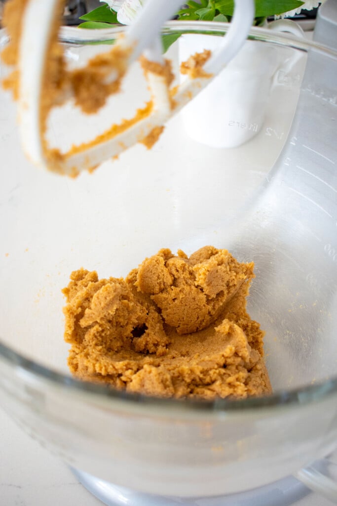 creamed butter and sugar in a glass mixing bowl on a white marble counter.