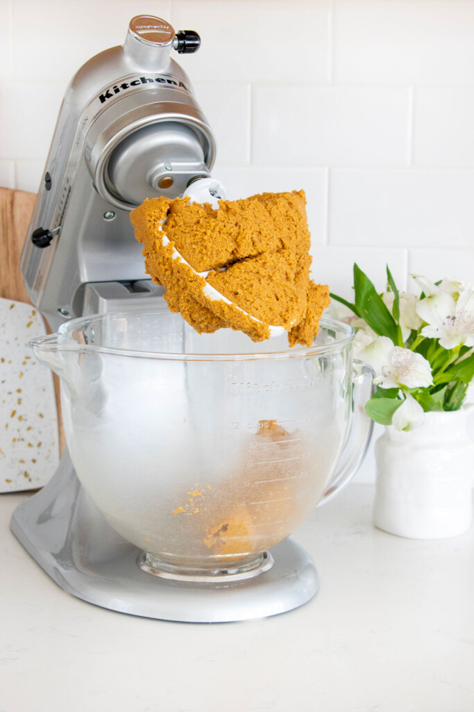 pumpkin spice cookie dough in a stand mixer on a white marble counter.