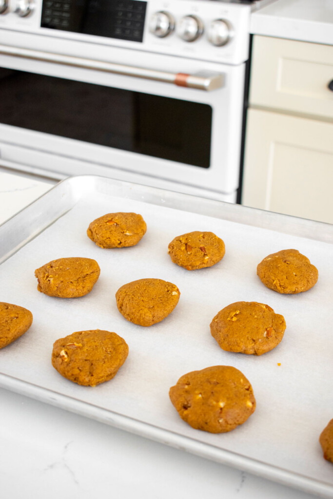 pecan pumpkin spice cookie dough on a baking sheet on a white marble counter.