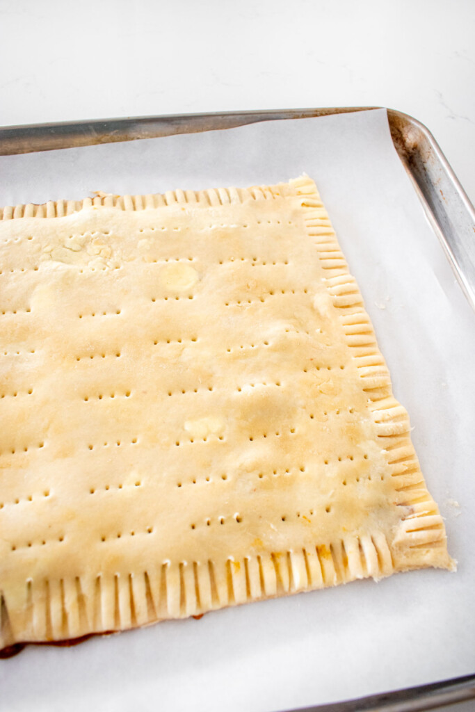 giant pumpkin spice pop tart that has vent holes poked in it on a baking sheet.