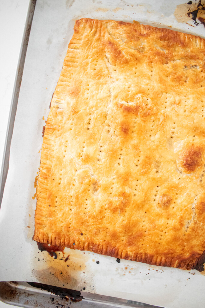 baked pumpkin spice pop tart on a baking sheet on a marble counter.