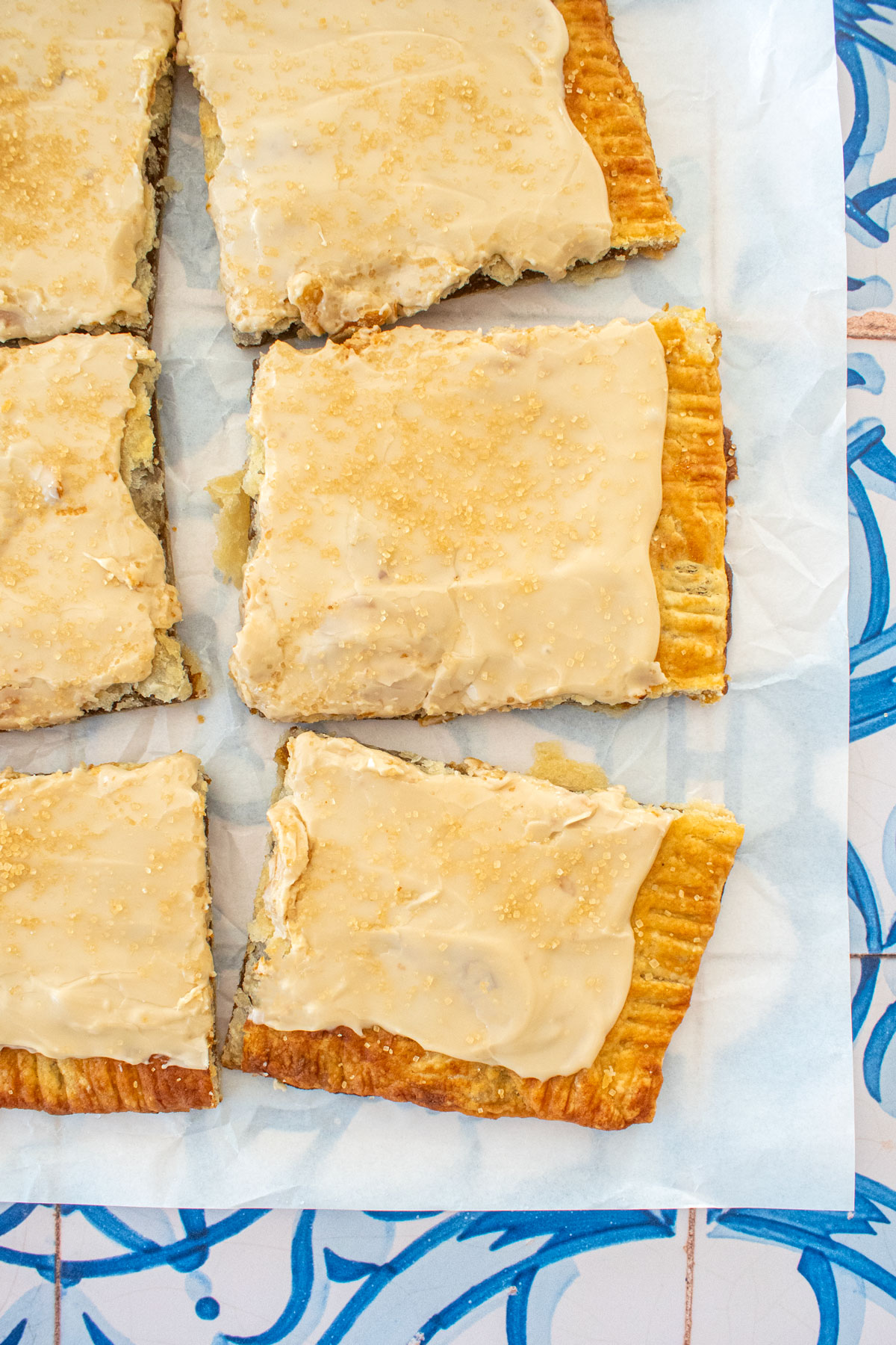 pumpkin spice pop tarts on a piece of parchment paper on a blue tile table.