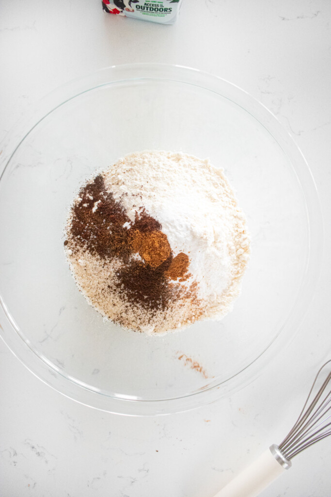 dry ingredients for eggnog waffles in a glass mixing bowl on a white marble counter.