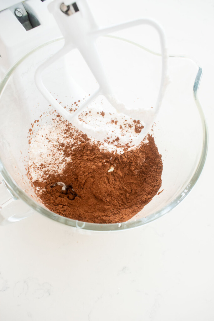ingredients for mint meltaways in a glass mixing bowl on a white marble counter.