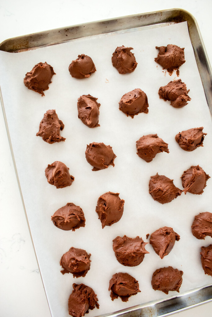 mint meltaways portioned out on a baking sheet on a white marble counter.