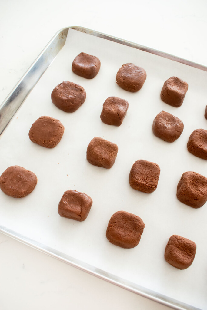 mint meltaways formed into squares on a baking sheet on a white marble counter.