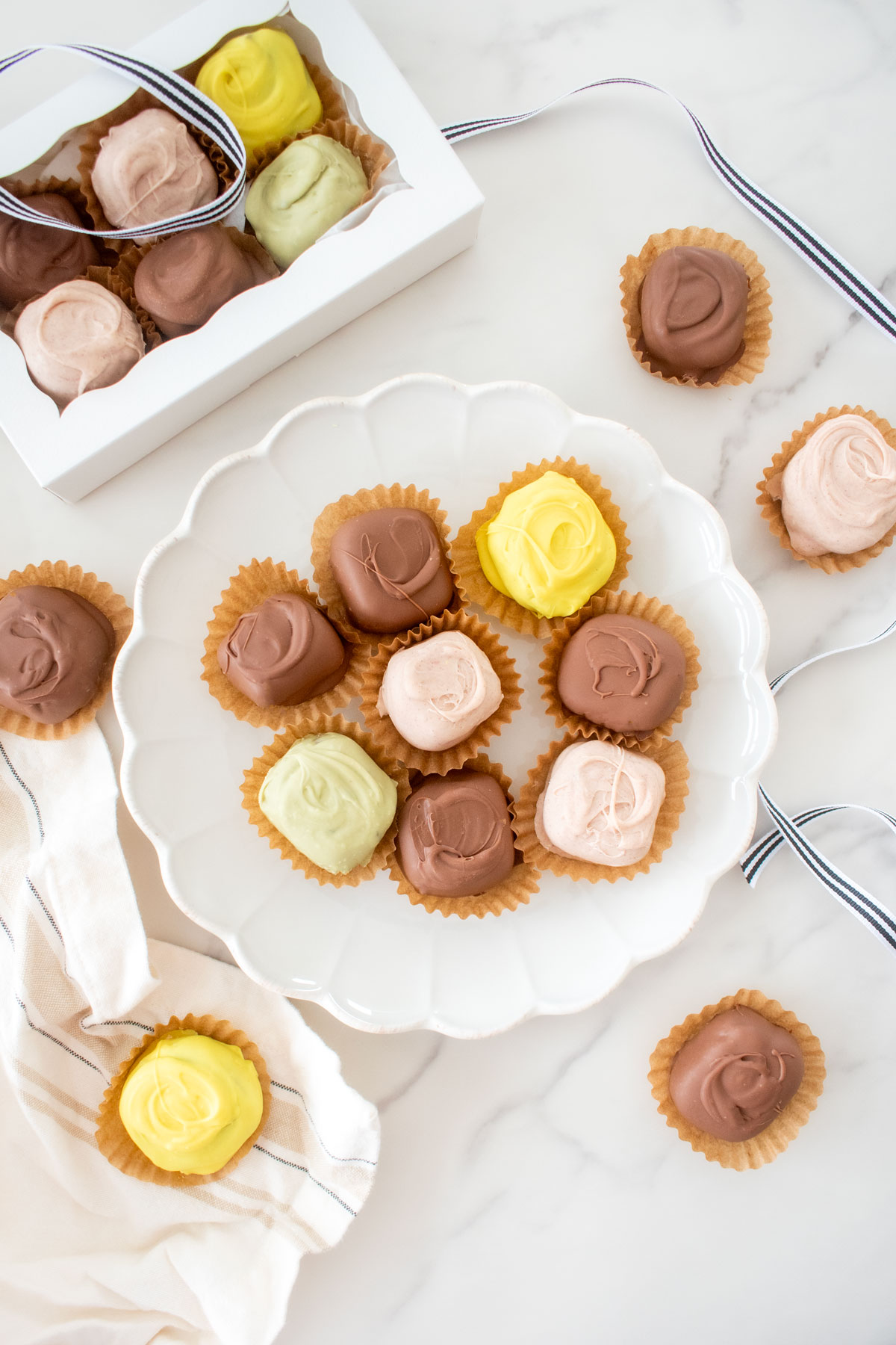 white ruffle plate of mint meltaways in pastel colors on a white marble counter.