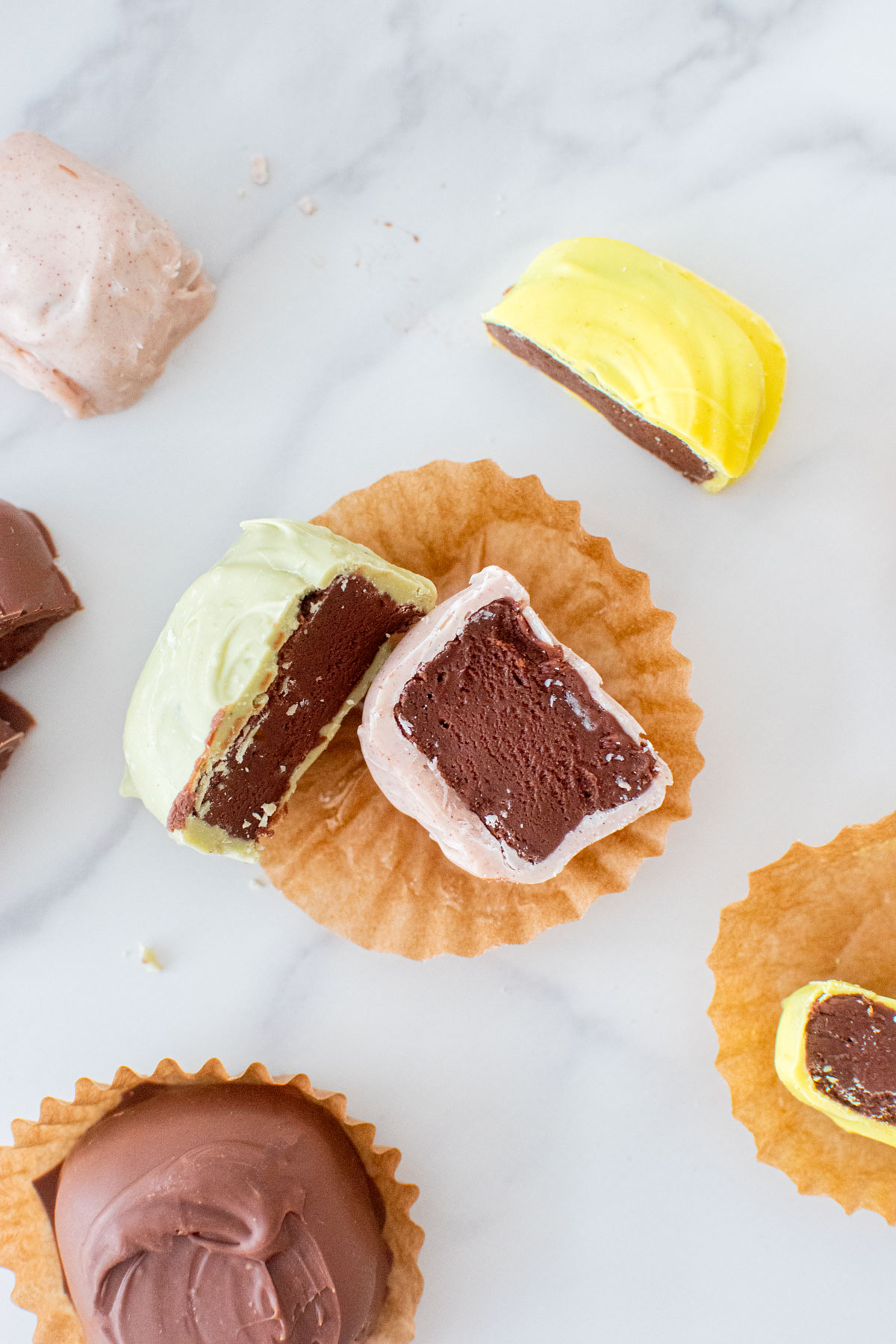 mint meltaway cut in half on a white marble counter revealing a creamy mint chocolate center.