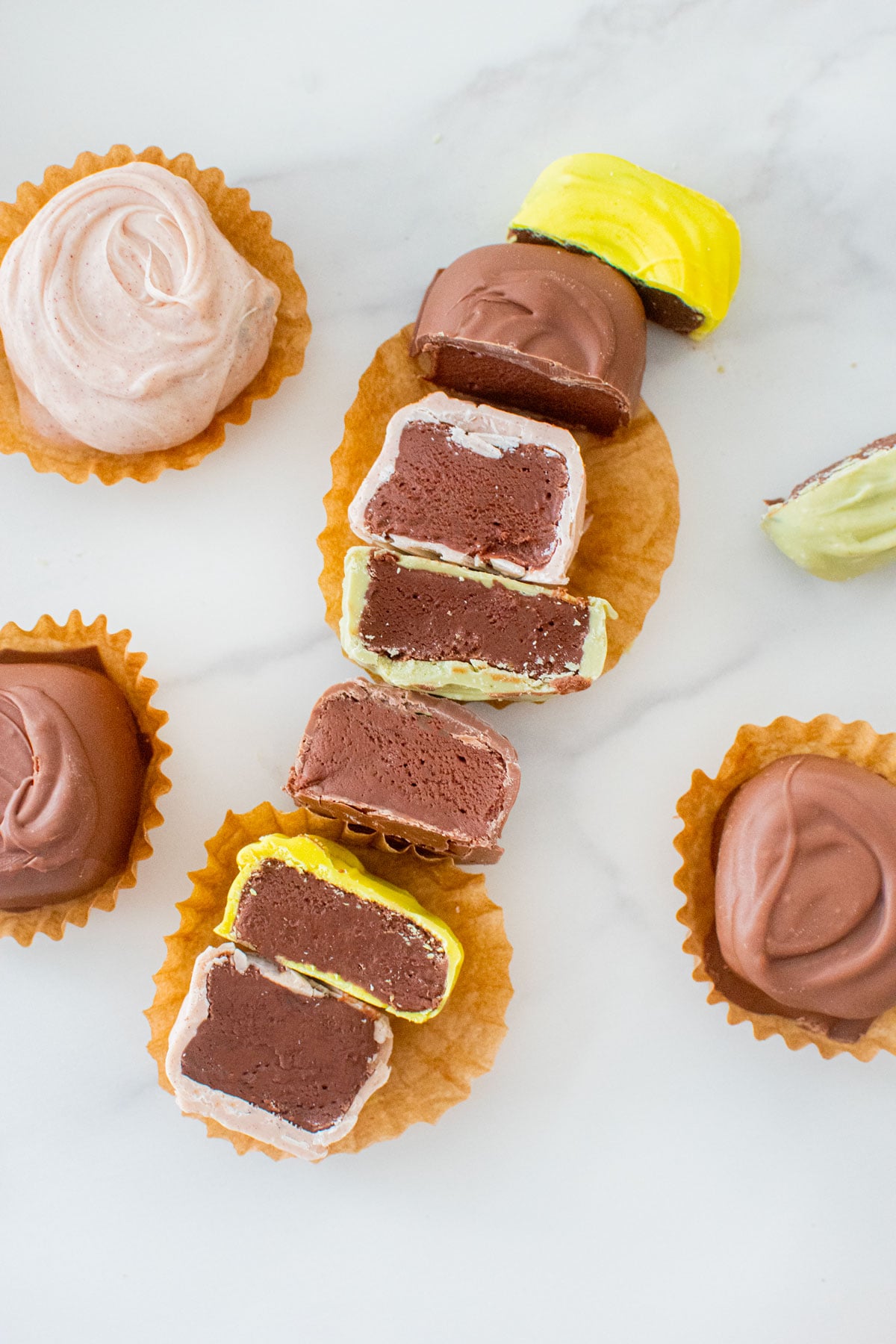 mint meltaways cut in half on a white marble counter revealing a creamy mint chocolate center.