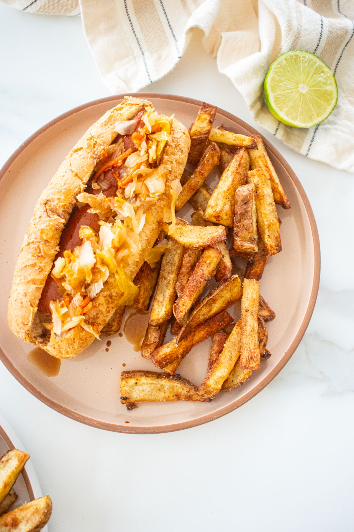 chinese five spice garlic fries on a plate with a hot dog with kimchee on a marble counter.