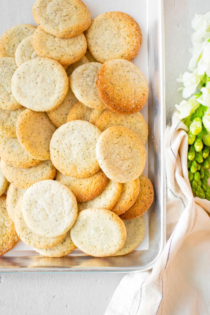 baking sheet of earl grey sandwich cookies on a grey table with fresh flowers.