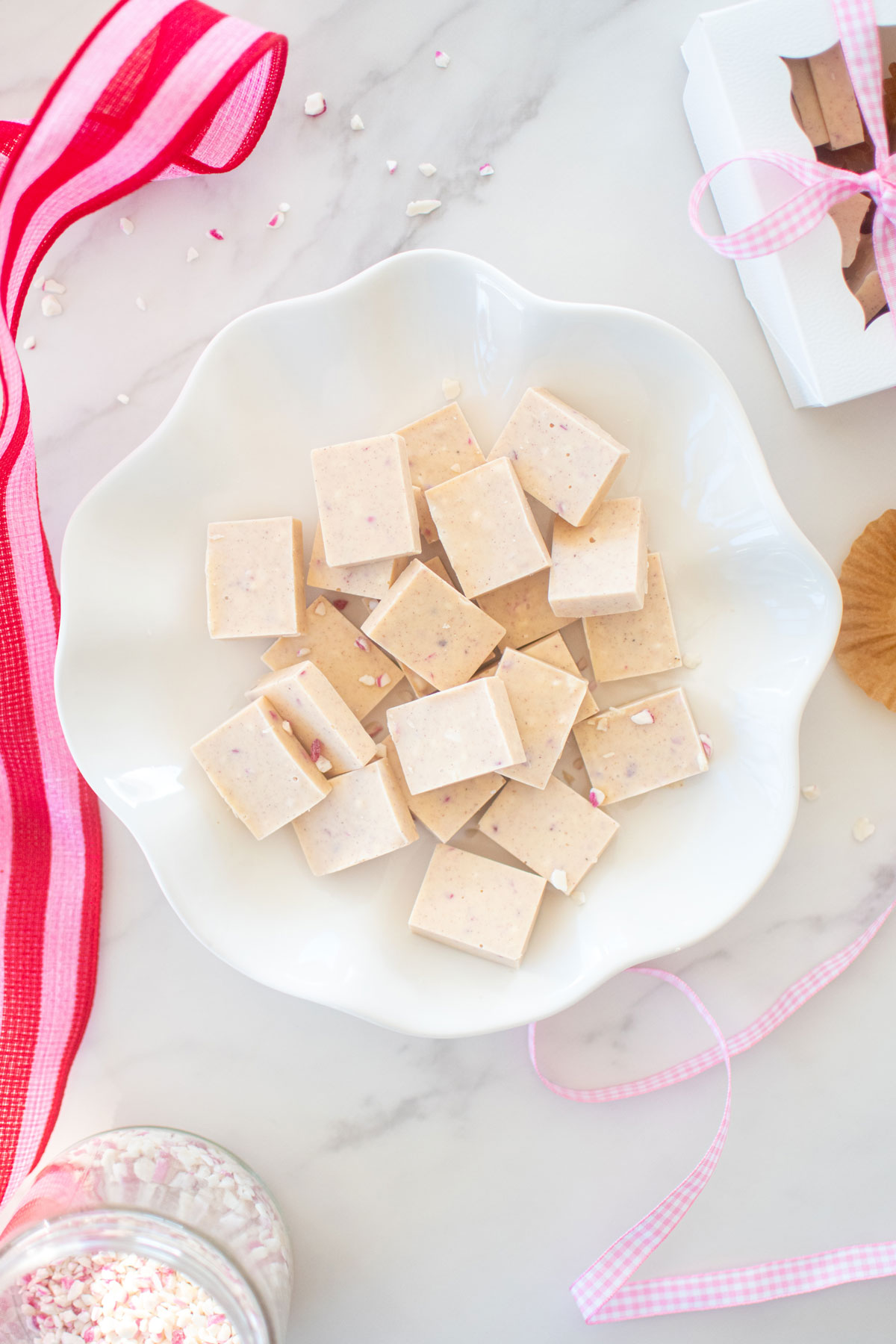 pink peppermint ice squares on a white ruffle plate on a marble counter.