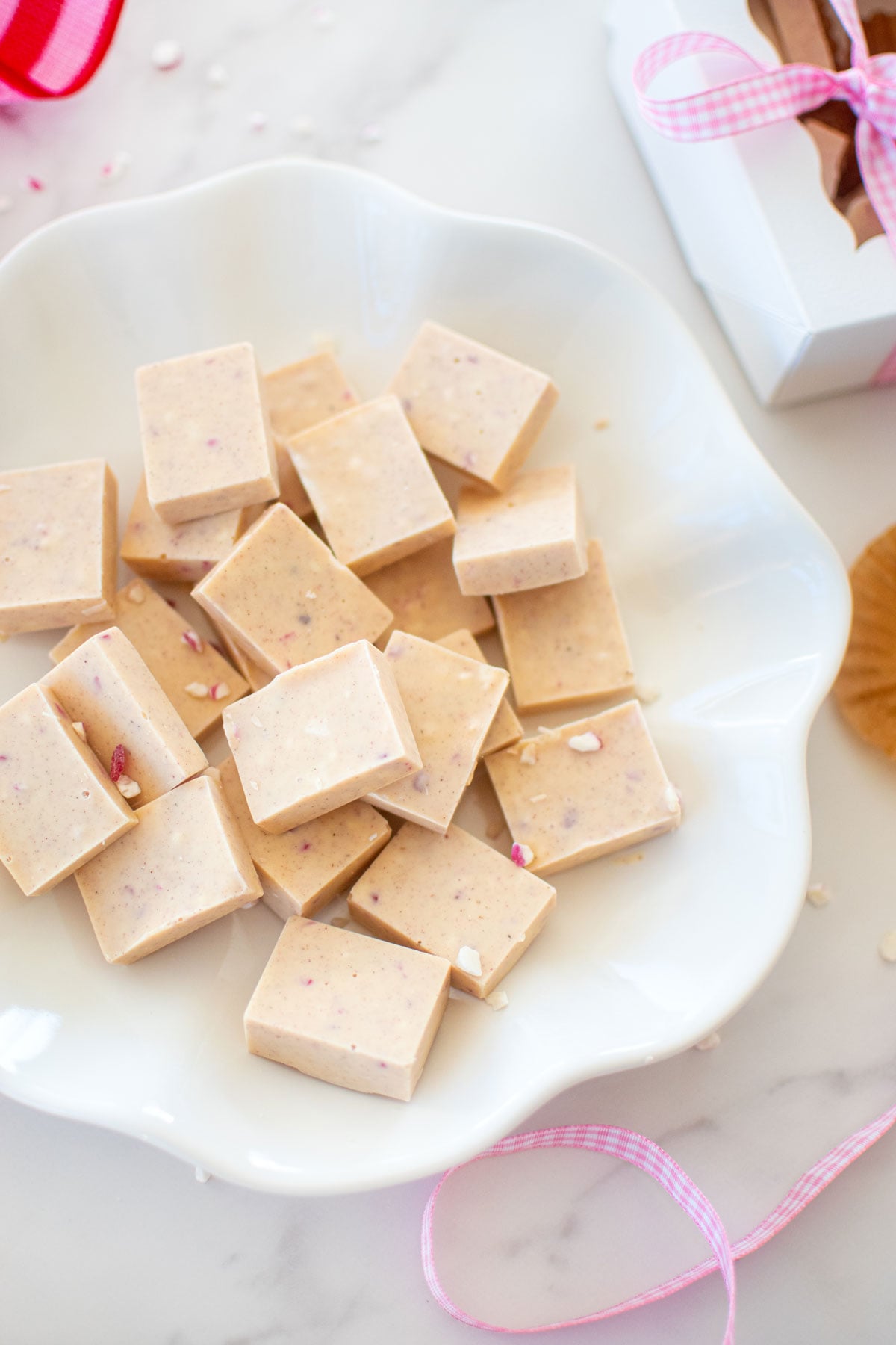 pink peppermint ice squares on a white ruffle plate on a marble counter.