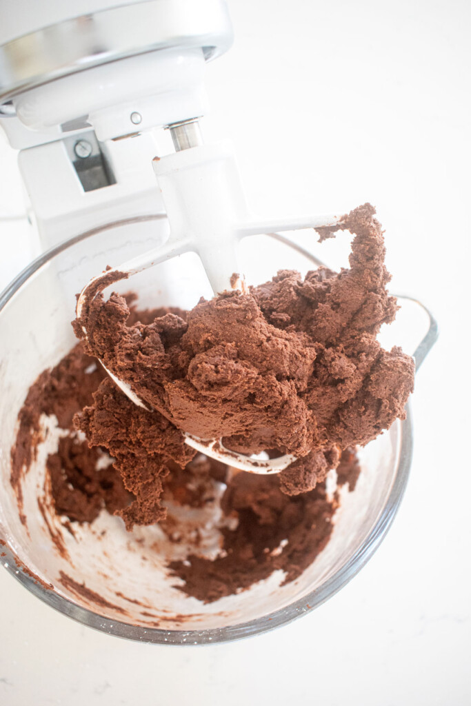 chocolate cookie dough in a glass mixing bowl on a marble counter.