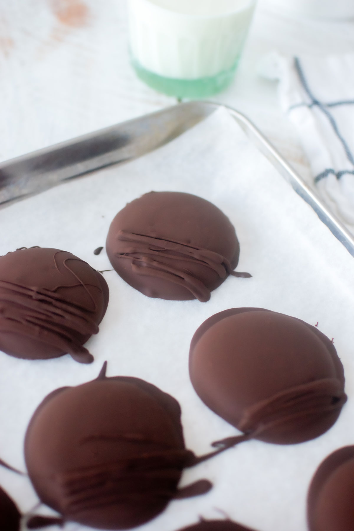chocolate covered thin mint cookies on a baking sheet with a glass of milk.