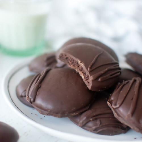 homemade organic thin mint cookies on a plate with a glass of milk on a white wood table.
