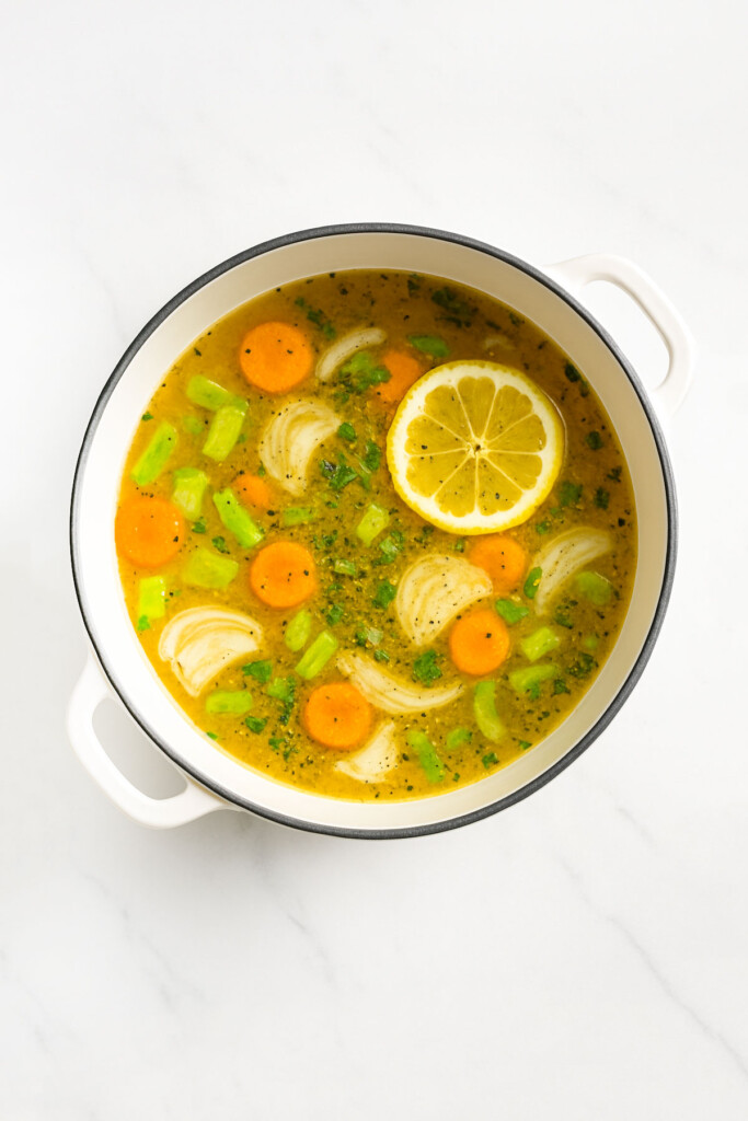 Meyer lemon chicken and wild rice soup in a white dutch oven on a white marble countertop.