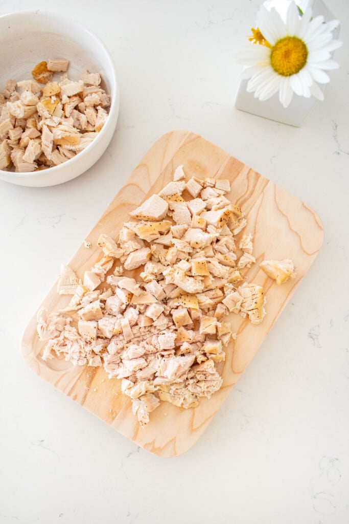 wood cutting board with chopped chicken breast on a marble counter.