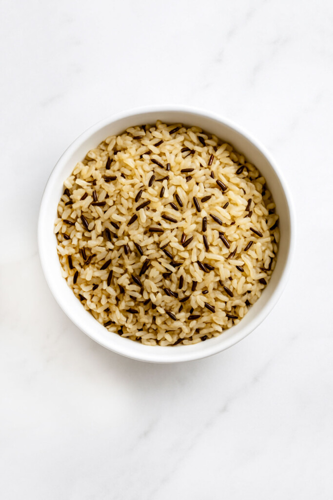 Wild rice in a white bowl on a white marble countertop.