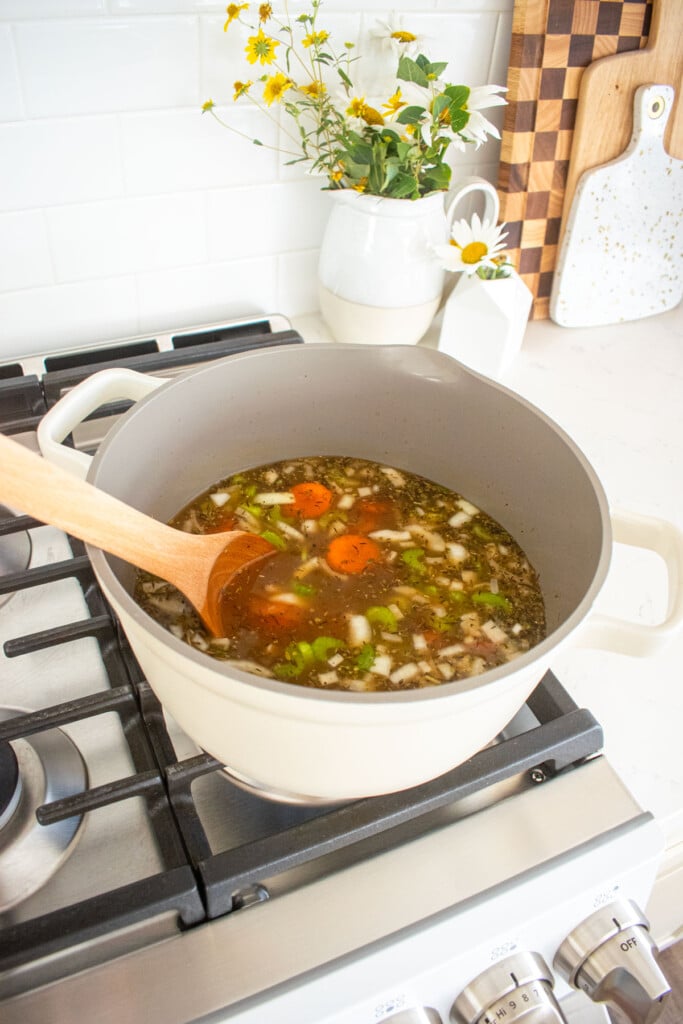 meyer lemon chicken wild rice soup in a dutch oven being cooked on the stovetop.