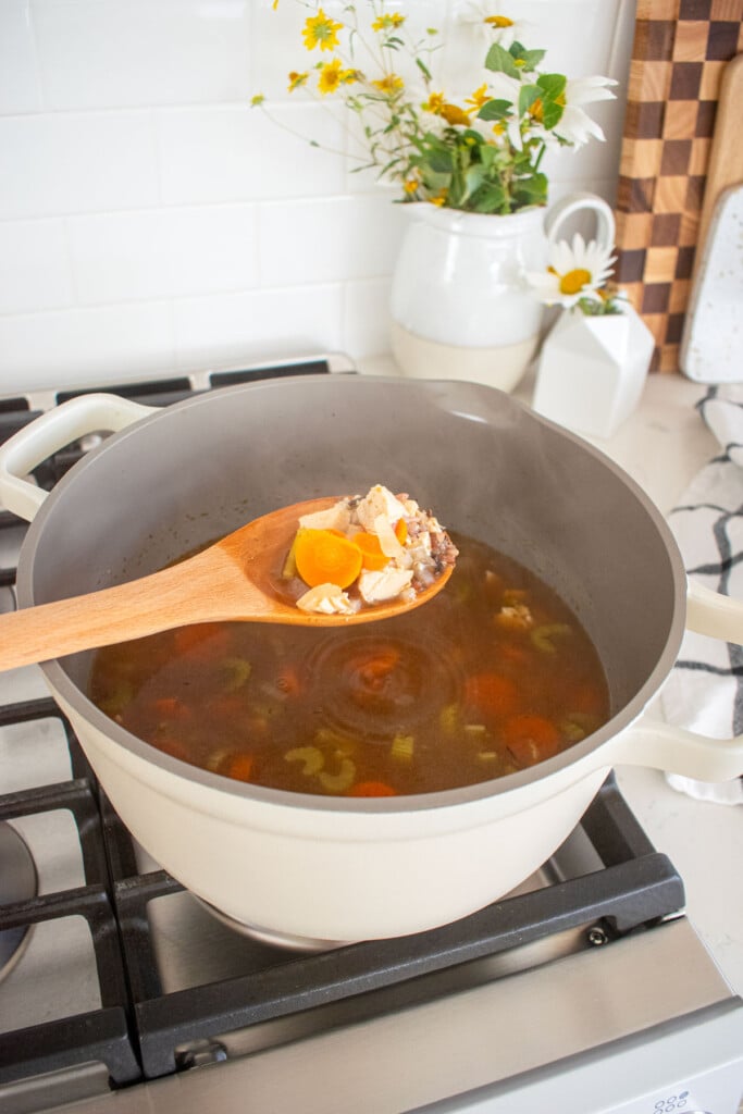 meyer lemon chicken wild rice soup in a dutch oven on the stovetop with a wooden spoon.