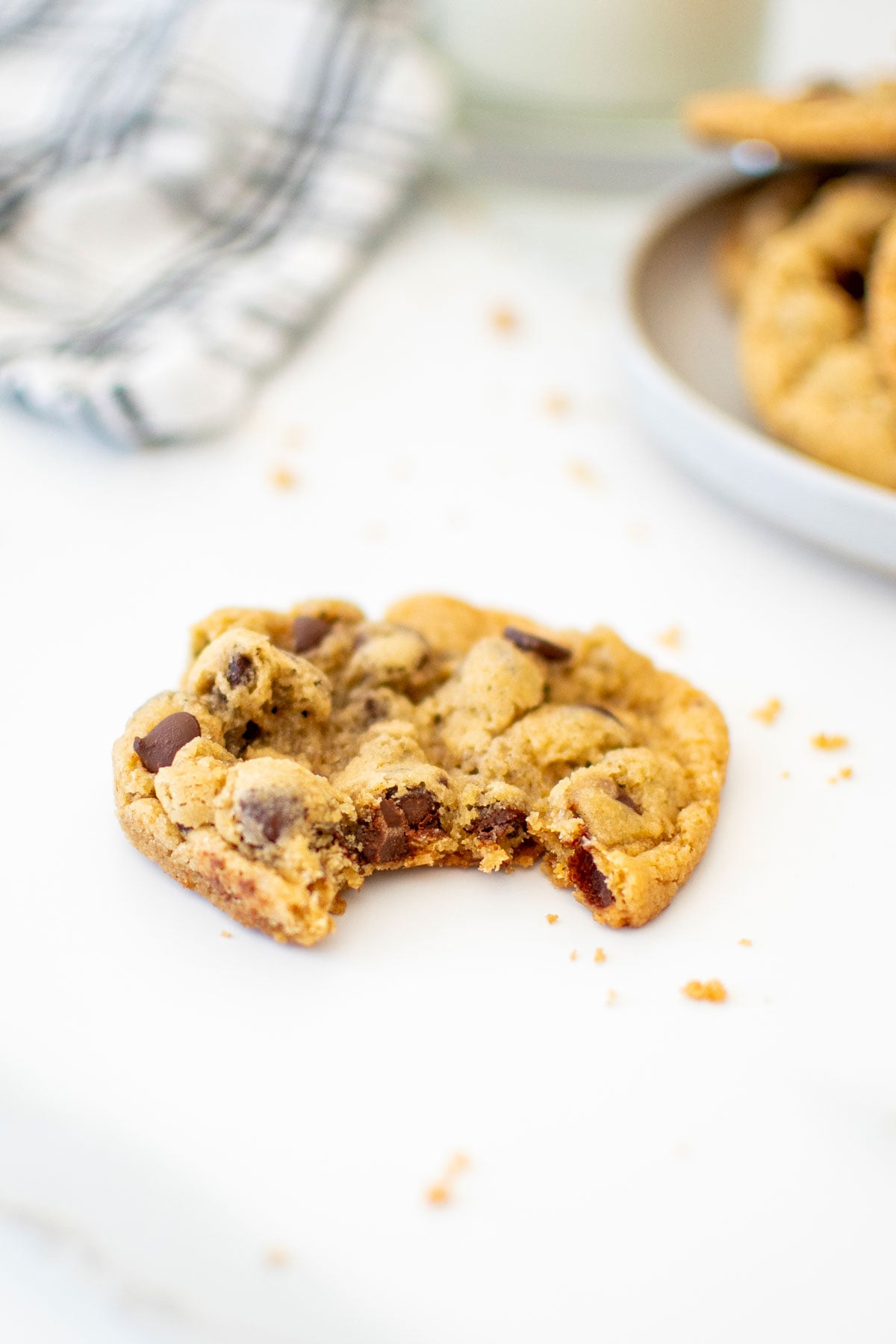 eggless chocolate chip cookie with a bite taken out on a white marble counter.