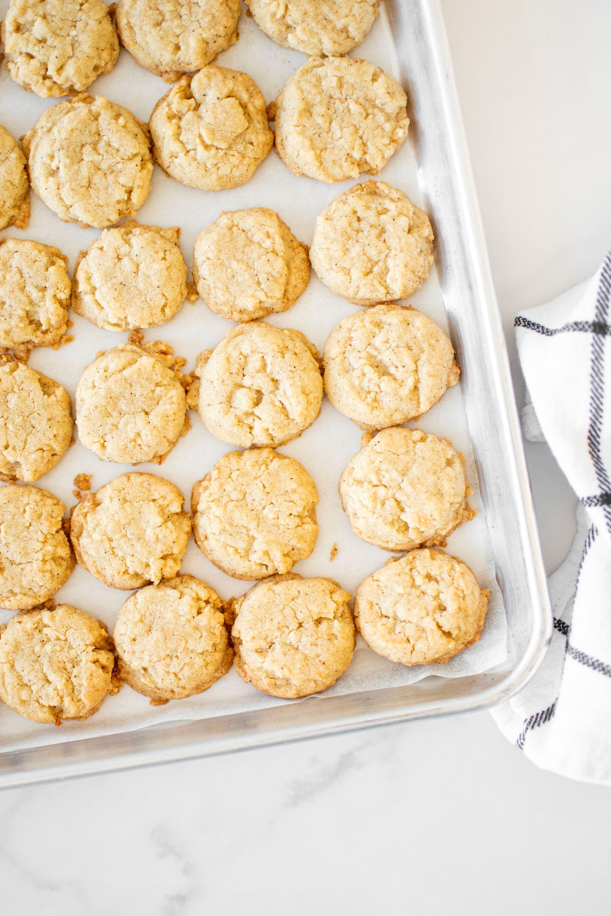 coconut vanilla bean mini cookies on a baking sheet on a marble counter.