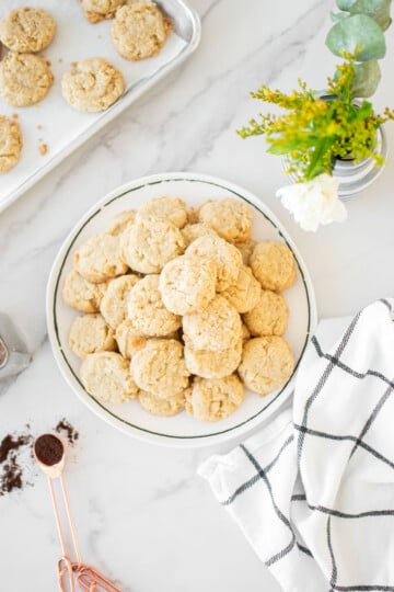 coconut vanilla bean mini cookies on a plate on a marble counter with fresh flowers.