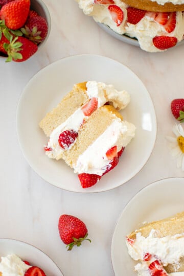 eggless strawberry shortcake sliced on cake plates with fresh strawberries.