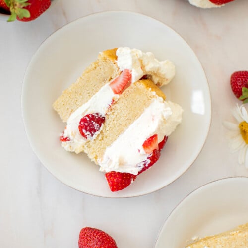 eggless strawberry shortcake sliced on cake plates with fresh strawberries.