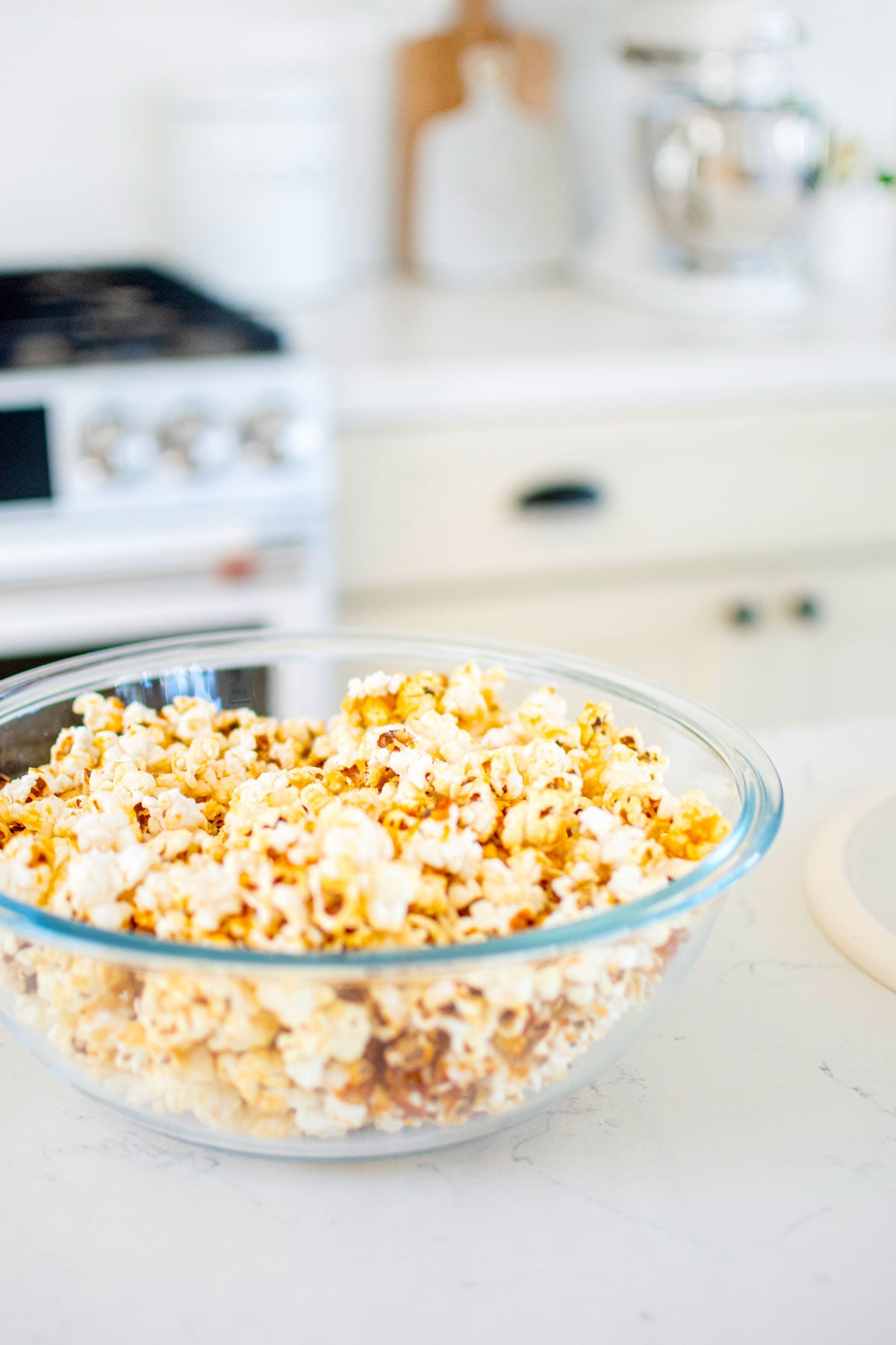 homemade kettle corn with coconut oil in a glass bowl on a white marble countertop.
