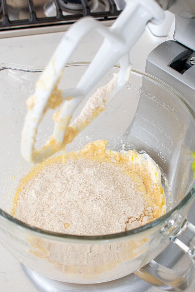 ingredients for simple vanilla cupcakes in a glass stand mixing bowl on a white marble counter.