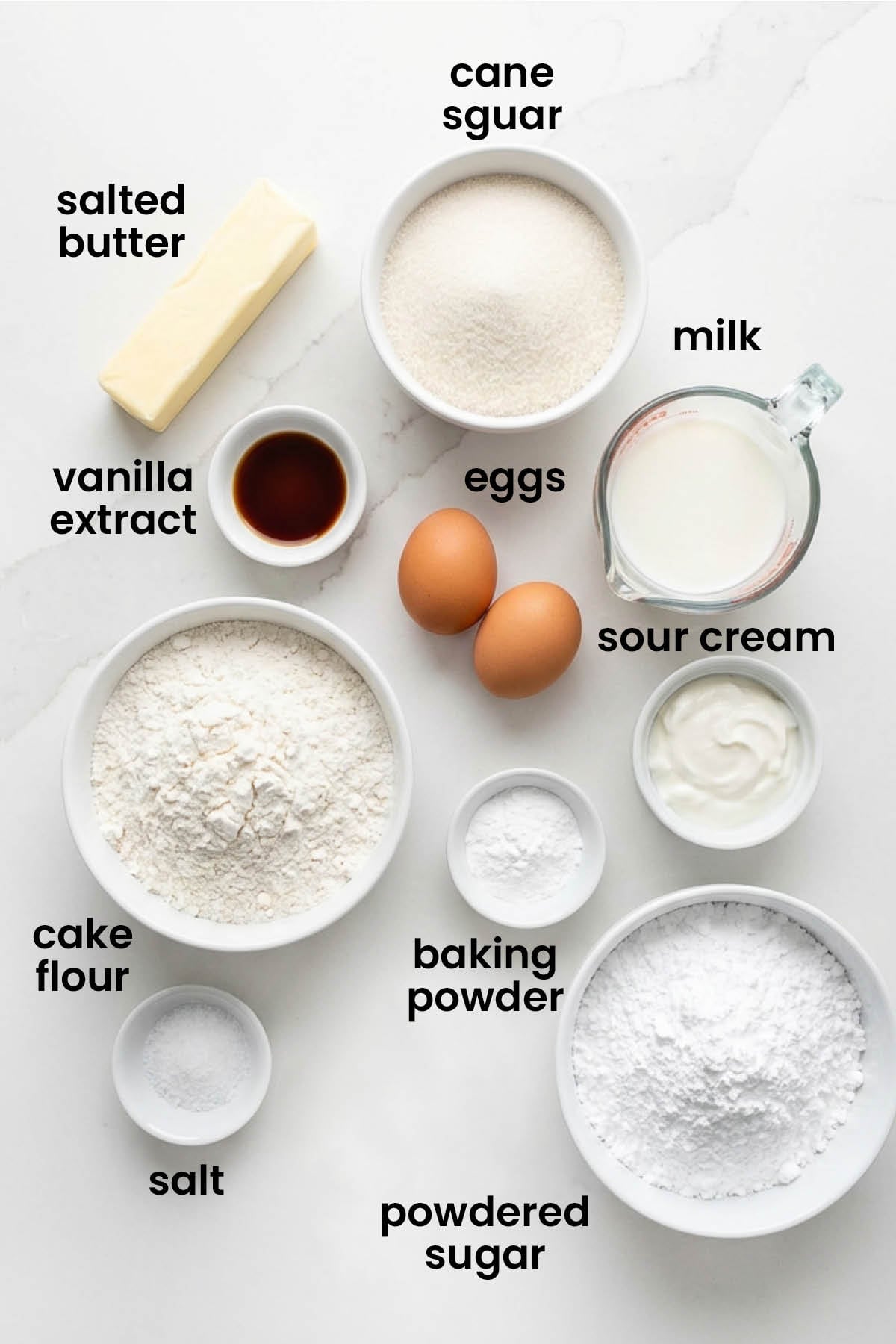individual ingredients for simple vanilla cupcakes laid out against a white background.