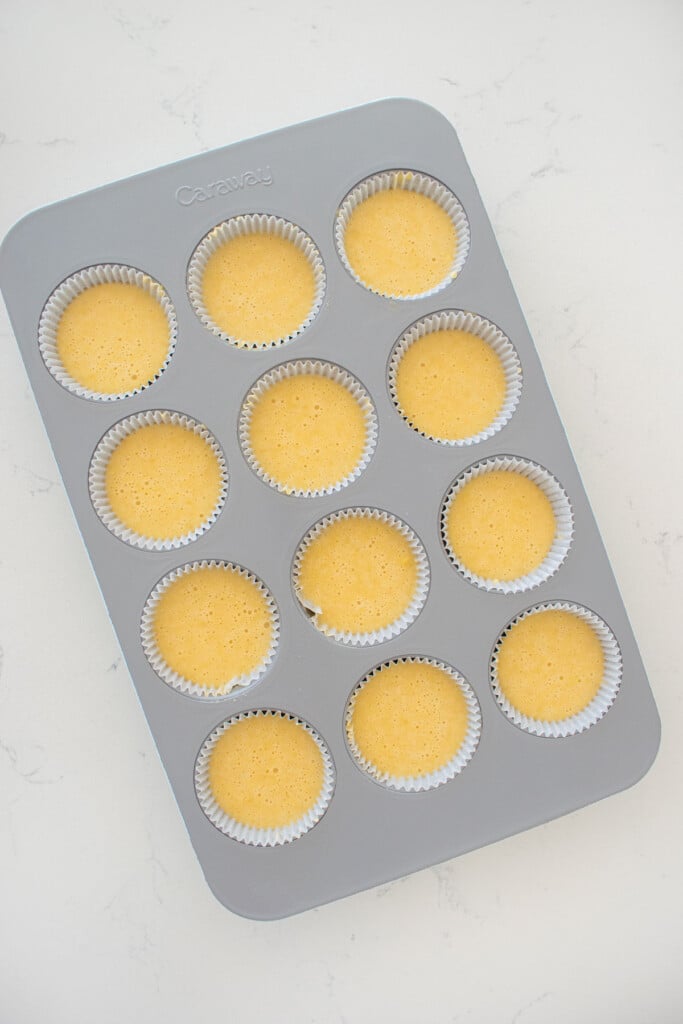 vanilla cupcake batter in a cupcake pan on a white marble counter.