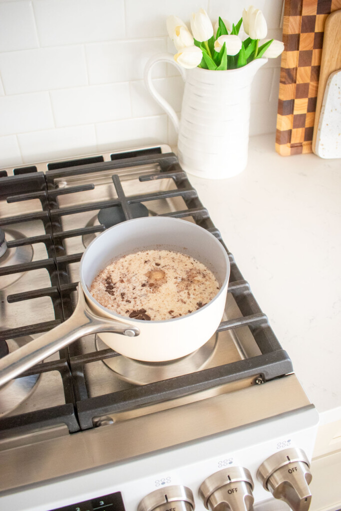 boozy pumpkin spice hot chocolate in a small pot on the stovetop.