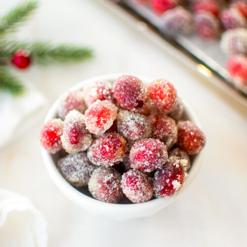 homemade sugared cranberries in a bowl on a marble counter.