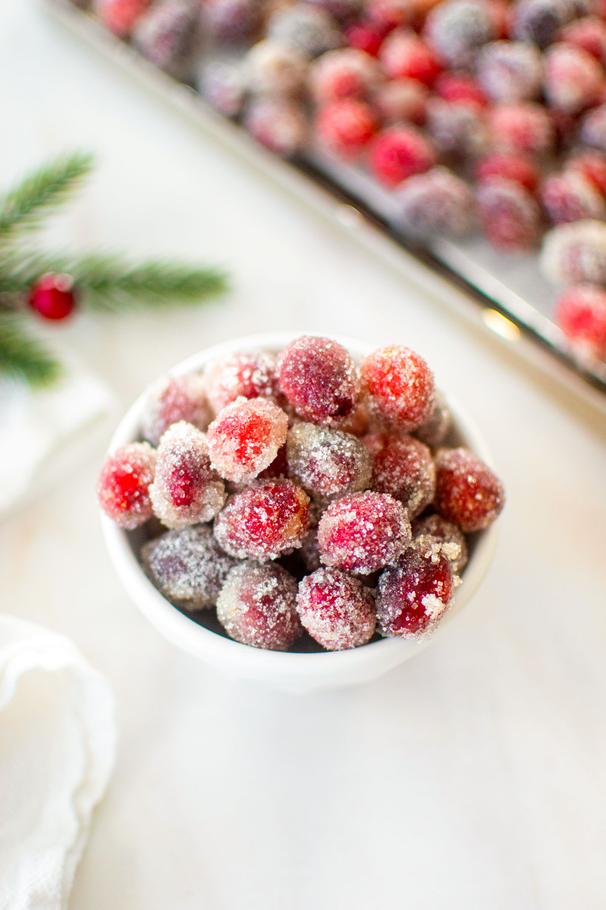 homemade sugared cranberries in a bowl on a marble counter.
