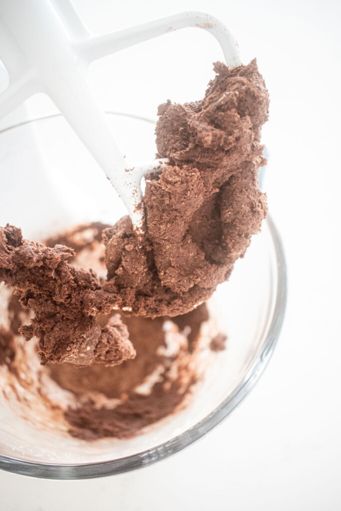 hot chocolate bomb dough mixed in a glass mixing bowl on a white marble counter.