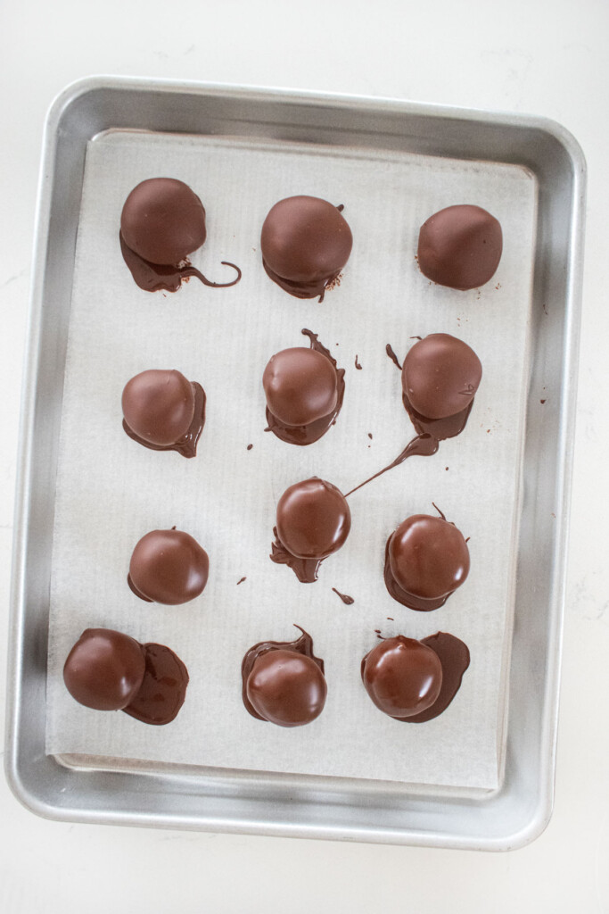 hot chocolate bombs coated in chocolate on a sheet pan.
