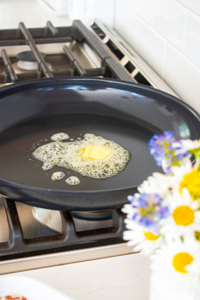 butter melting in a black skillet on the stovetop.